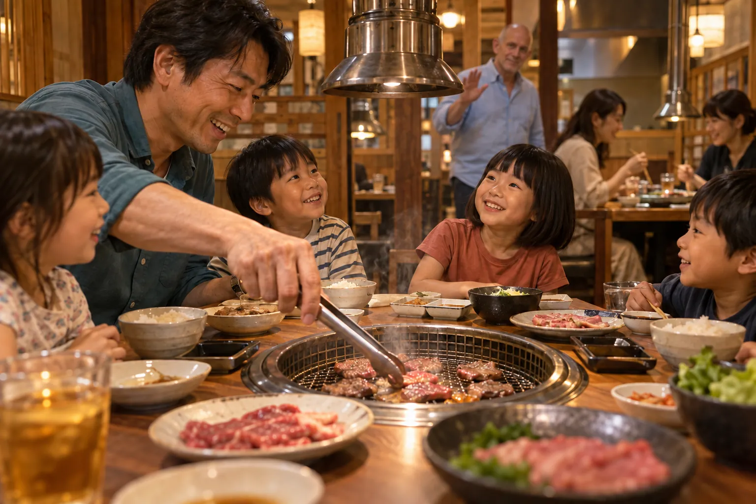 A Japanese father turns meat with tongs as four children watch, while mothers eat at another table and a bald visitor greets the family.