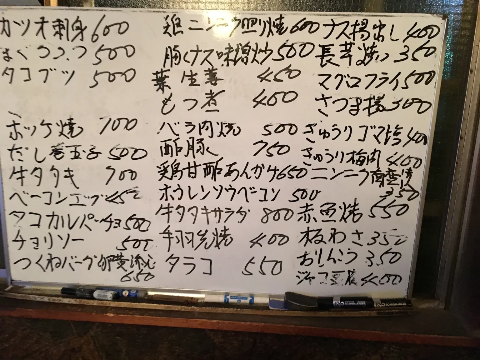手書きの料理名と値段がびっしり書かれたホワイトボードのお品書き。