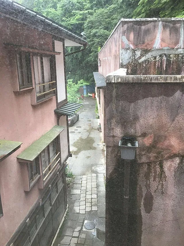A narrow rain-wet lane between weathered old buildings at the back of the inn.