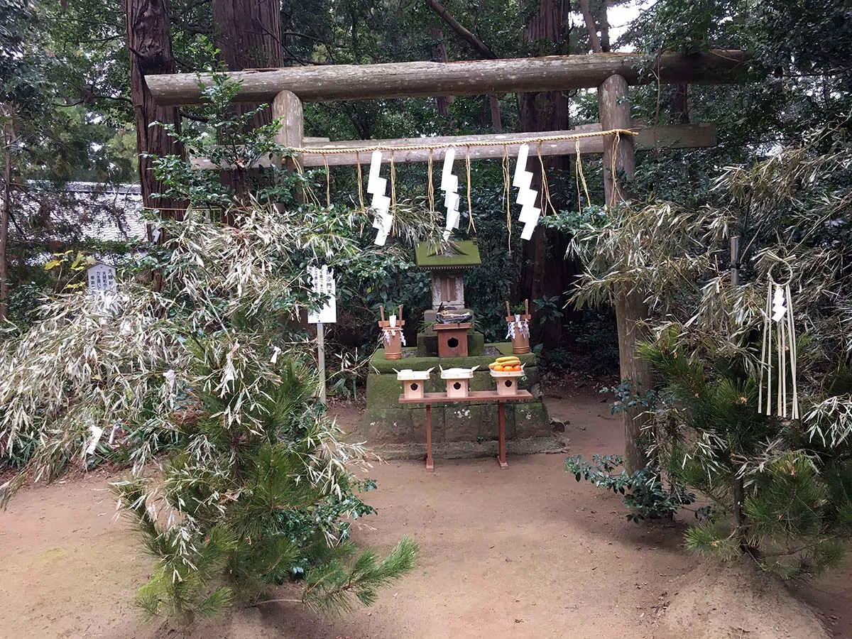 側高神社の杉木立の中に建つ小さな石の祠。白い紙垂が下げられている。