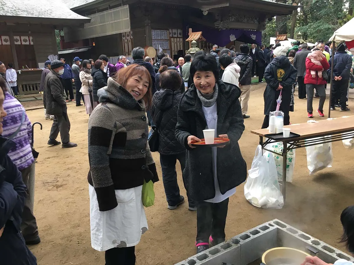 来場者に甘酒をふるまう、笑顔の女性ふたり。